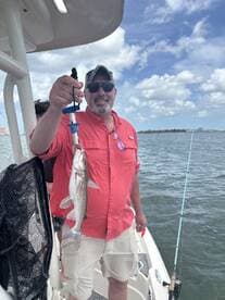 A proud angler holding a freshly caught fish while enjoying a day on the water, showcasing a successful fishing trip.