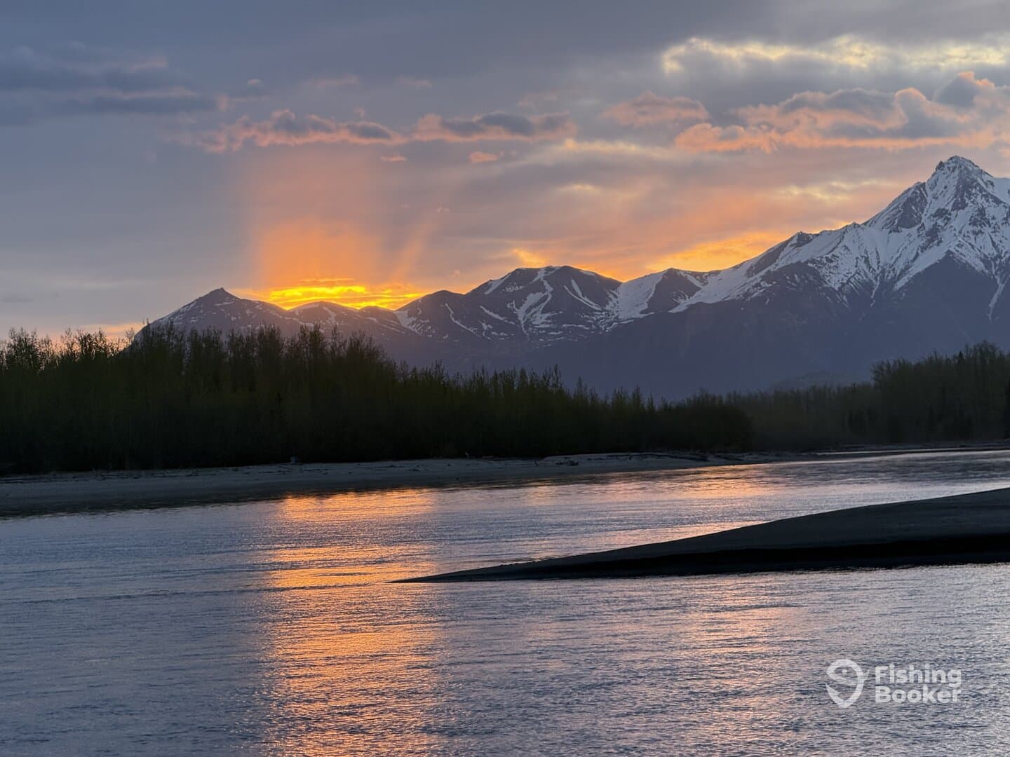 Scenic view of a sunset over mountains reflecting on a river, showcasing the natural beauty of the fishing environment.