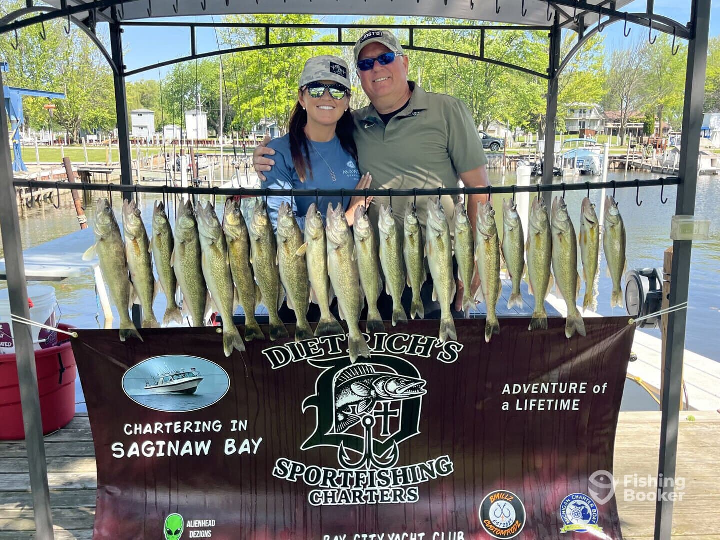 A couple proudly poses with their catch of Walleye displayed on a board at Saginaw Bay, showcasing a successful fishing charter experience.