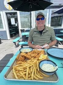 A man enjoying a meal with fried fish and fries at a restaurant, showcasing a casual dining experience.