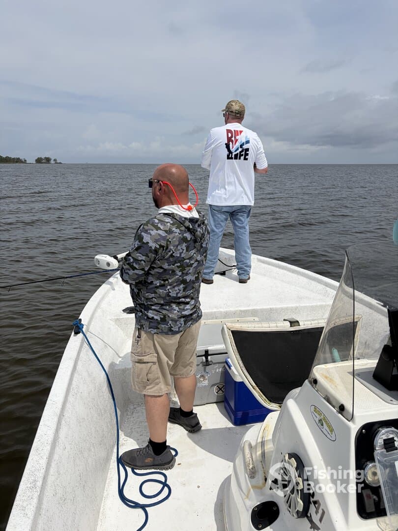 Two anglers casting lines from a small boat on a calm waterway, showcasing a relaxed fishing experience.