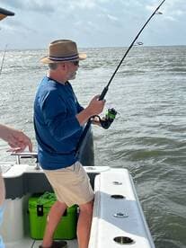 An angler casting a line while fishing from a boat in a coastal environment, showcasing the excitement of the catch.