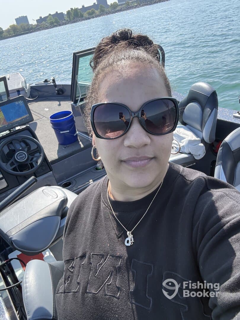 A woman takes a selfie inside a fishing boat, showcasing the helm and seating area while enjoying a sunny day on the water.