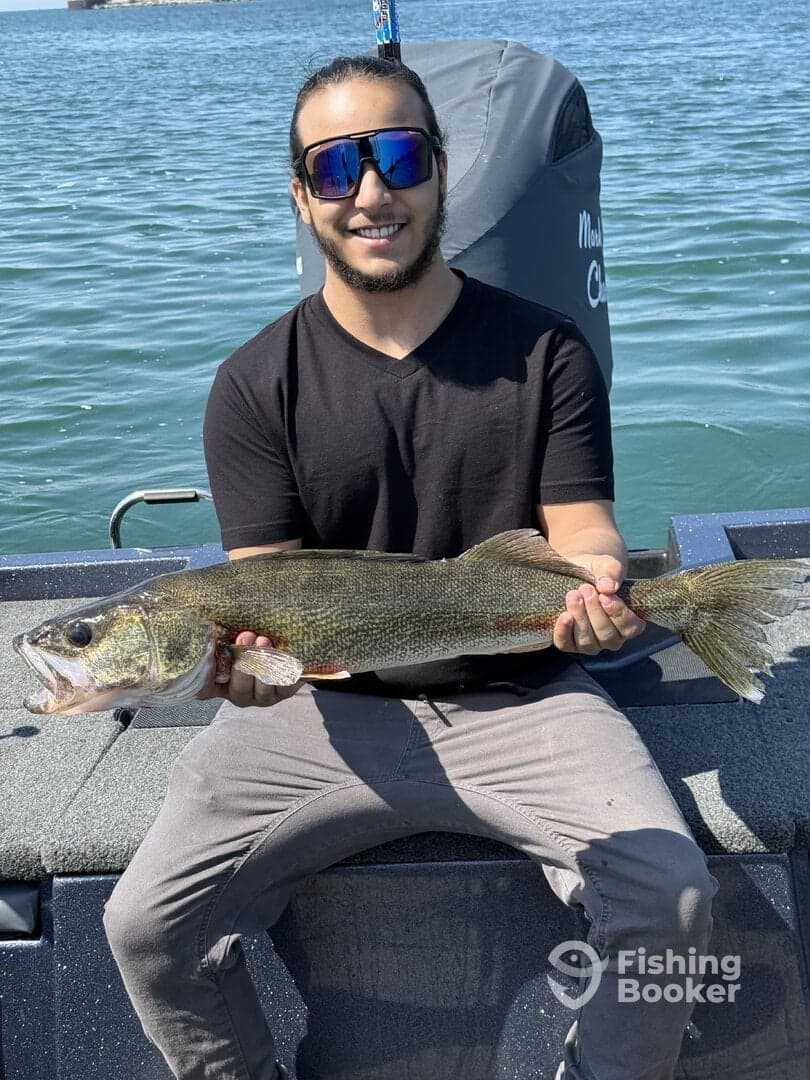 Angler proudly displaying a large Walleye while fishing on a boat, showcasing a successful day on the water.