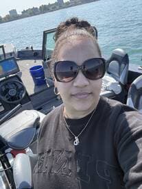 A woman takes a selfie inside a fishing boat, showcasing the helm and seating area while enjoying a sunny day on the water.