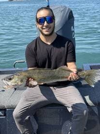 Angler proudly displaying a large Walleye while fishing on a boat, showcasing a successful day on the water.