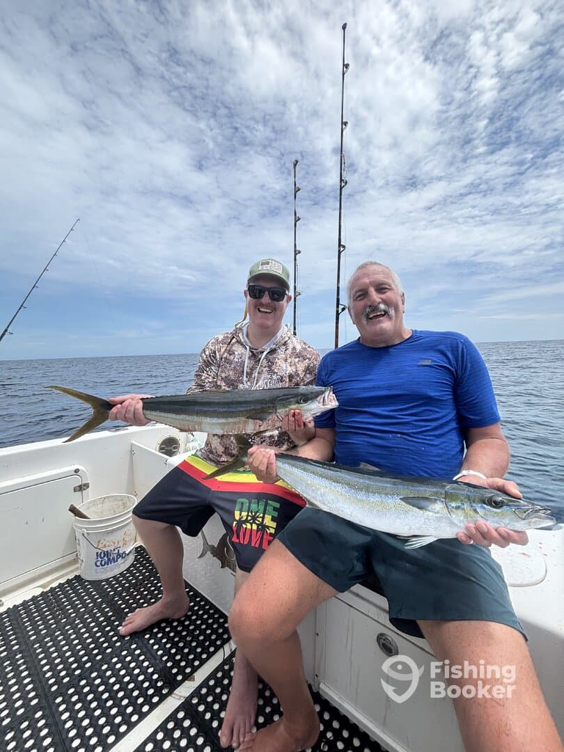 Two anglers proudly displaying their catch of Mackerel while fishing on a boat, enjoying a day on the water.