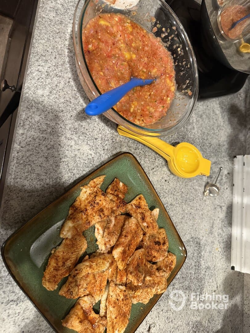 A plate of seasoned fish fillets ready for cooking, accompanied by a bowl of salsa, showcasing a delicious meal preparation.