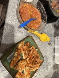 A plate of seasoned fish fillets ready for cooking, accompanied by a bowl of salsa, showcasing a delicious meal preparation.