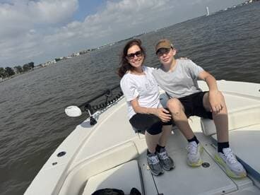 A mother and her son enjoying a day on the water, seated comfortably on the boat, with a scenic view of the shoreline.