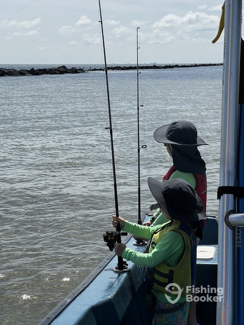 Two young anglers casting lines from a small boat, enjoying a day of fishing in calm waters.