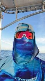 A fisherman wearing a full face mask and sunglasses, ready for a day on the water, captured inside the boat.