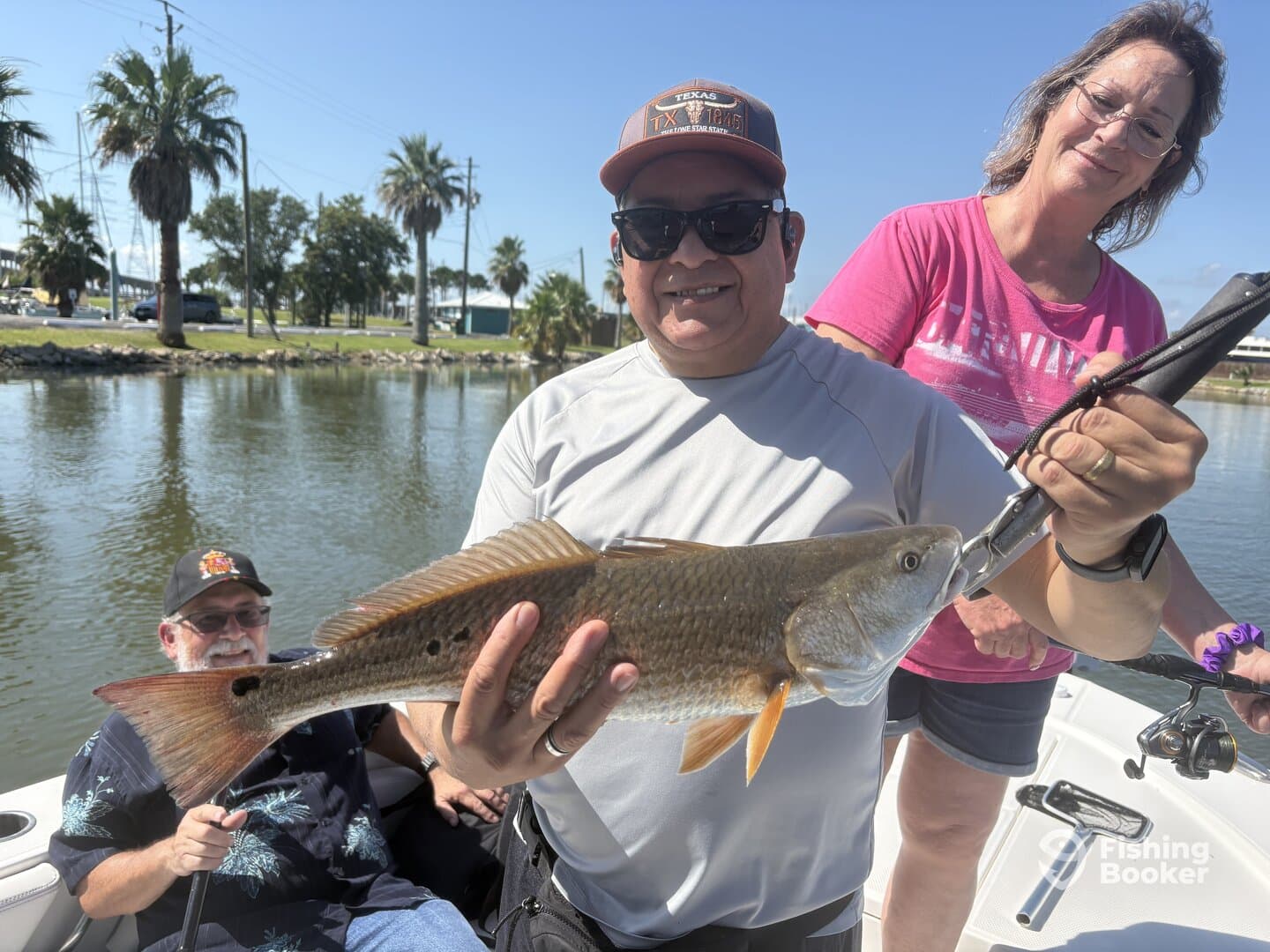 A proud angler displaying a Redfish while enjoying a sunny day on the water with family.