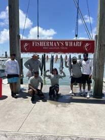 A group of anglers proudly displaying their catch of fish, including Snapper, at Fisherman's Wharf in Port Aransas, Texas.