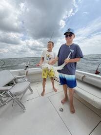 Two young anglers proudly displaying their catch on a fishing boat, enjoying a day on the water.