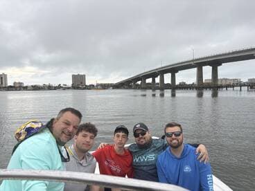 Group of friends enjoying a day on the water, with a bridge and cityscape in the background.