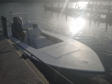 A sleek fishing boat docked at sunset, showcasing its modern design and spacious seating.
