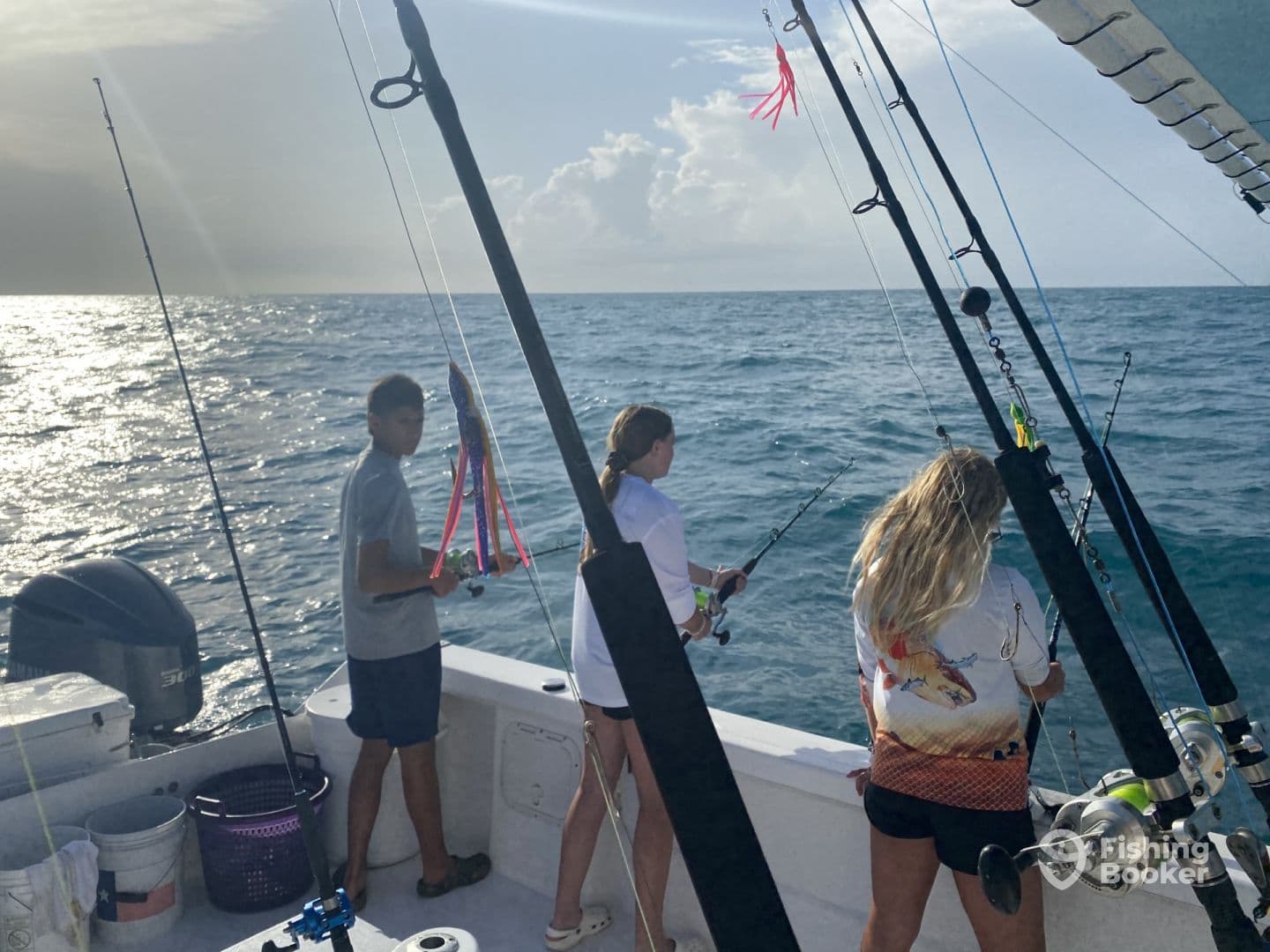 A group of young anglers actively fishing from a boat, showcasing their excitement as they prepare to reel in their catch on a sunny day at sea.