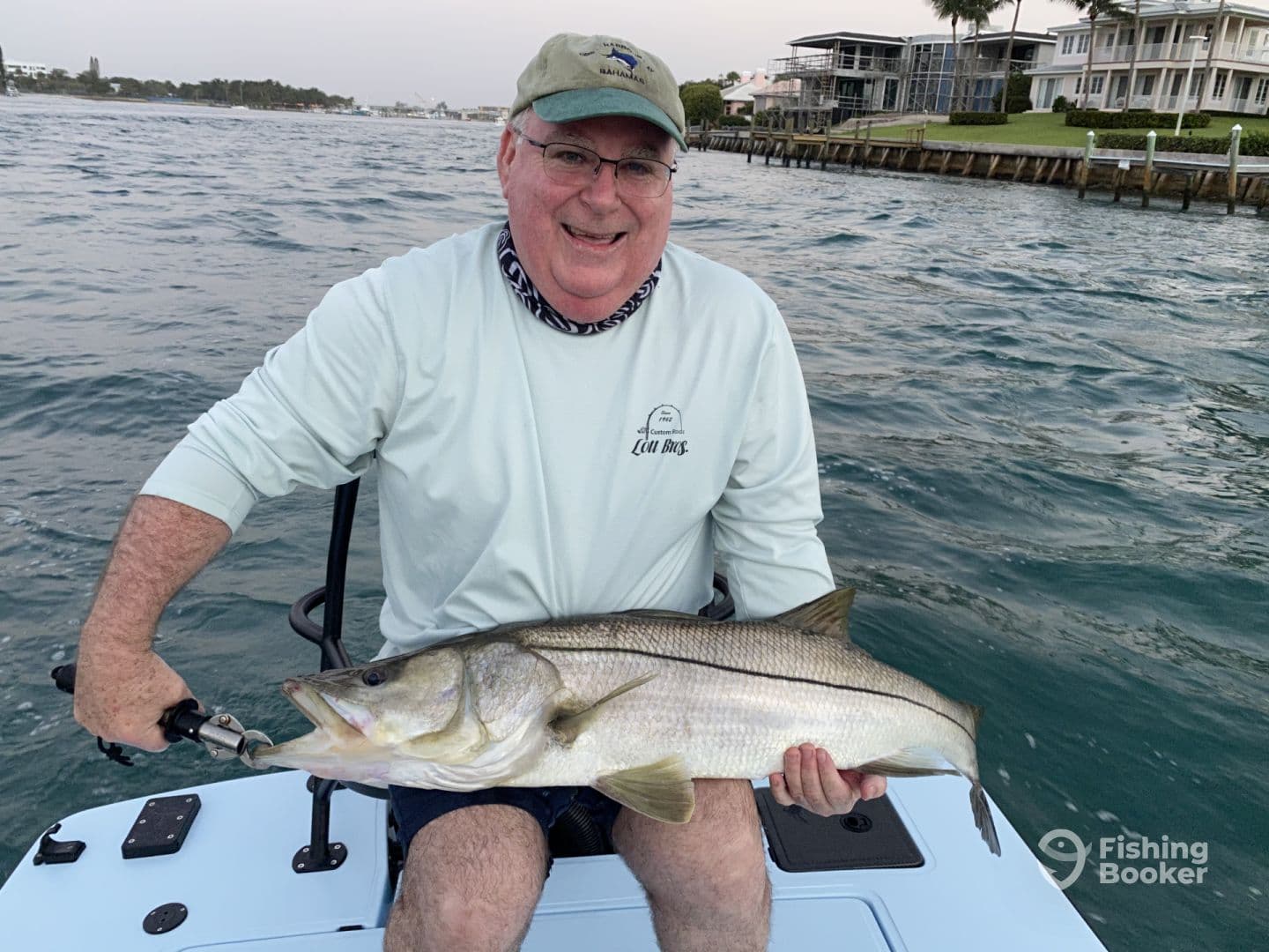 An angler proudly displaying a large Snook while fishing from a boat in a coastal waterway.