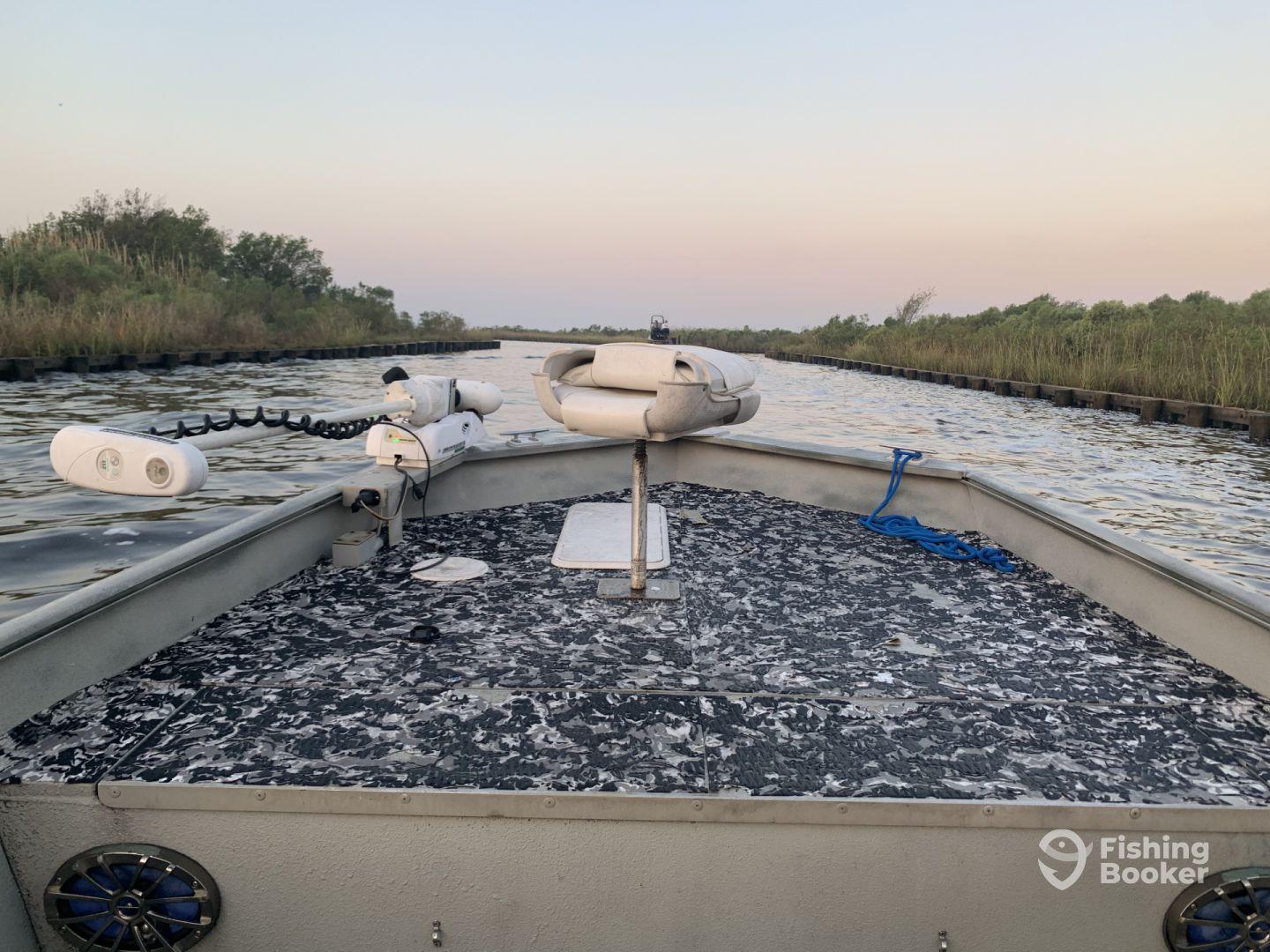 View from the helm of a fishing boat navigating through a serene waterway, surrounded by lush vegetation.