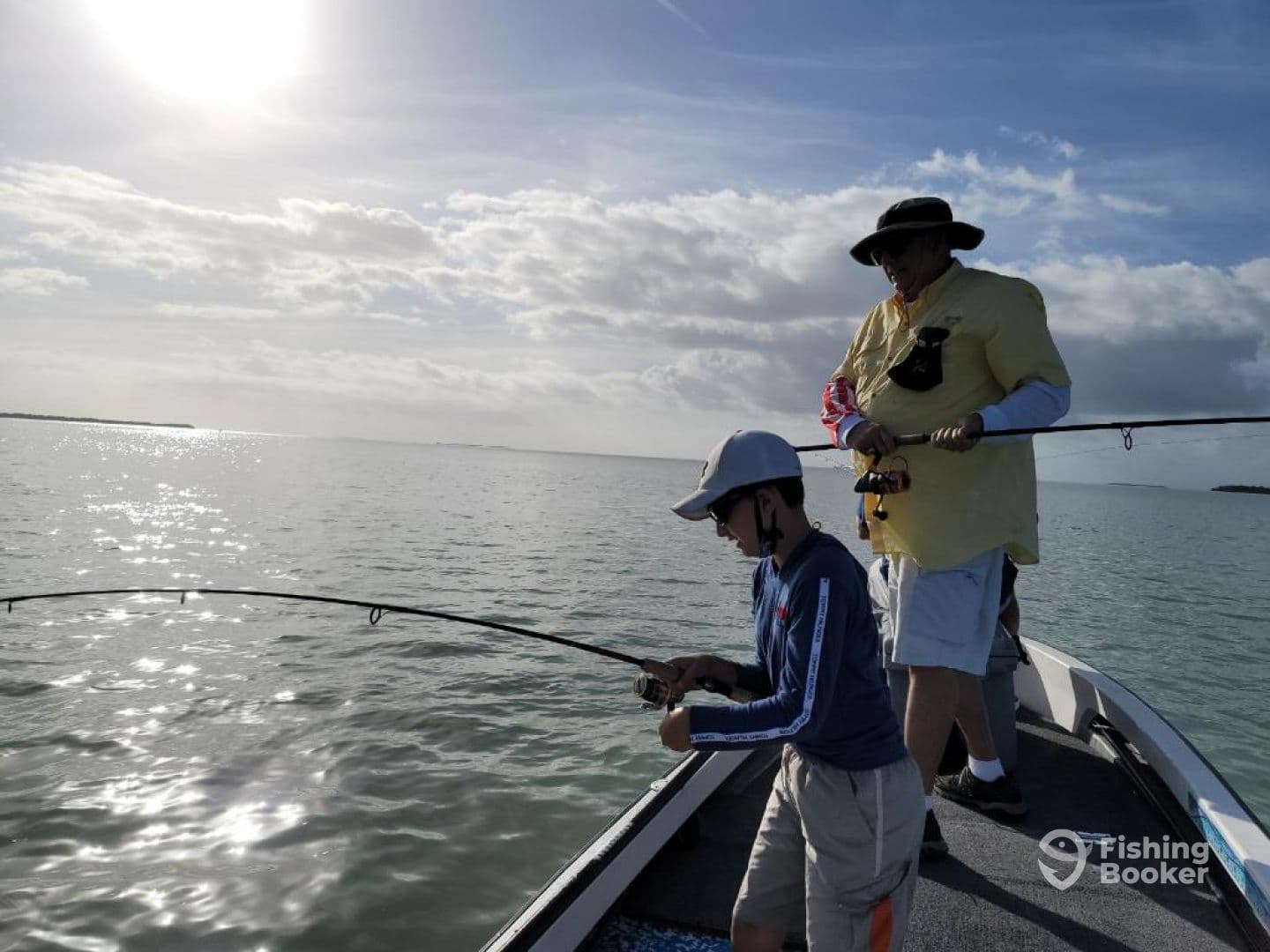 A young angler and an adult are actively fishing from a boat, casting lines into the sparkling waters, showcasing a family fishing experience.