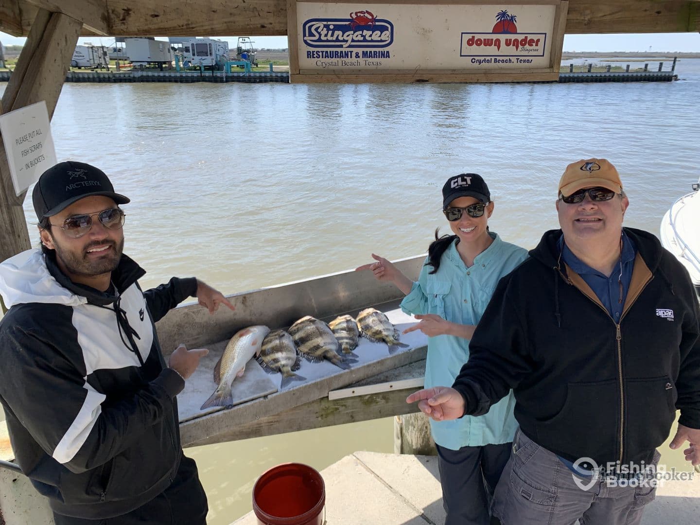 A group of anglers proudly showcasing their catch of the day, including a large Redfish and several Black Drum, at a marina in Crystal Beach, Texas.