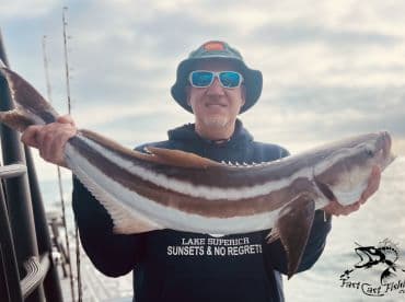 An angler proudly displaying a large Cobia caught during a fishing trip, showcasing the beautiful ocean backdrop.