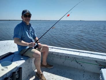 A solo angler fishing from a small boat in calm waters, showcasing a relaxed day on the water.