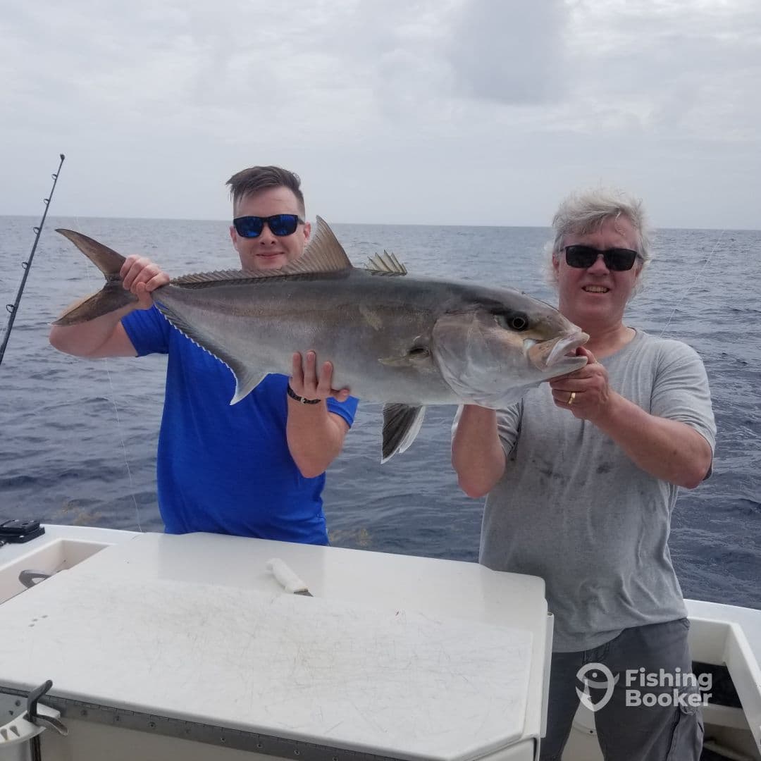 Two anglers proudly displaying a large Amberjack caught during a deep-sea fishing trip.
