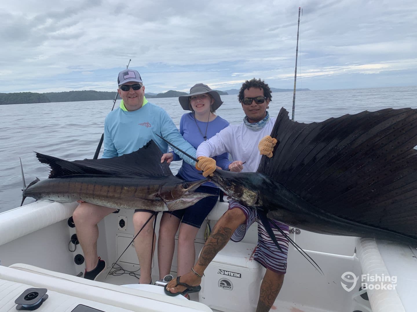 Two anglers proudly displaying their catch of Sailfish while on a sport fishing trip in open waters.