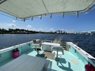 A young boy enjoying a sunny day on a fishing boat, seated at the helm while navigating through a scenic waterway.