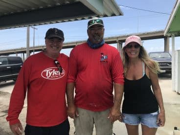 Three individuals posing together at a fishing location, with no visible catch or fishing activity.