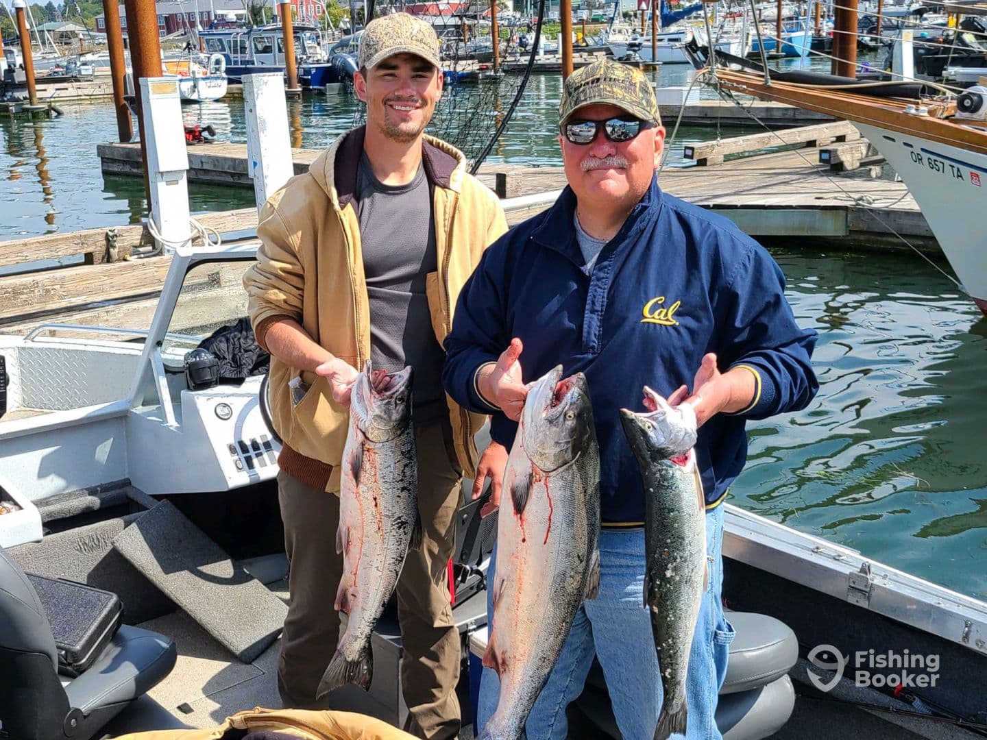 Two anglers proudly displaying their catch of Salmon while aboard a fishing boat at the marina.