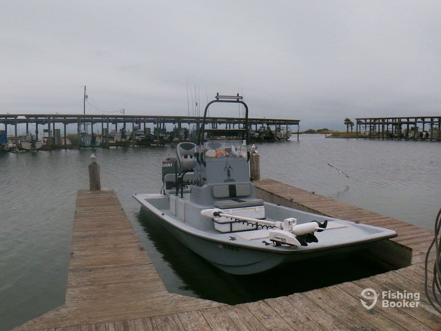 A sleek fishing boat docked at a marina, surrounded by other boats, under a cloudy sky.