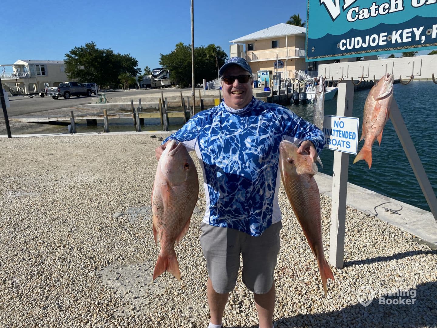 Angler proudly displaying two large Snapper at the dock in Cudjoe Key, showcasing a successful fishing trip.