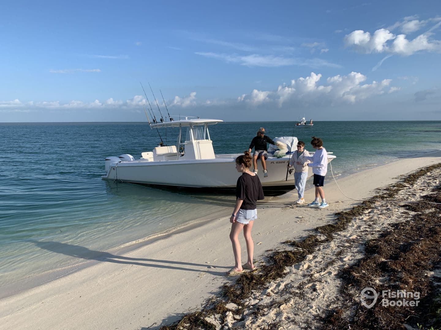 A family is seen on the beach with a center console boat, preparing for a fishing adventure in clear waters.