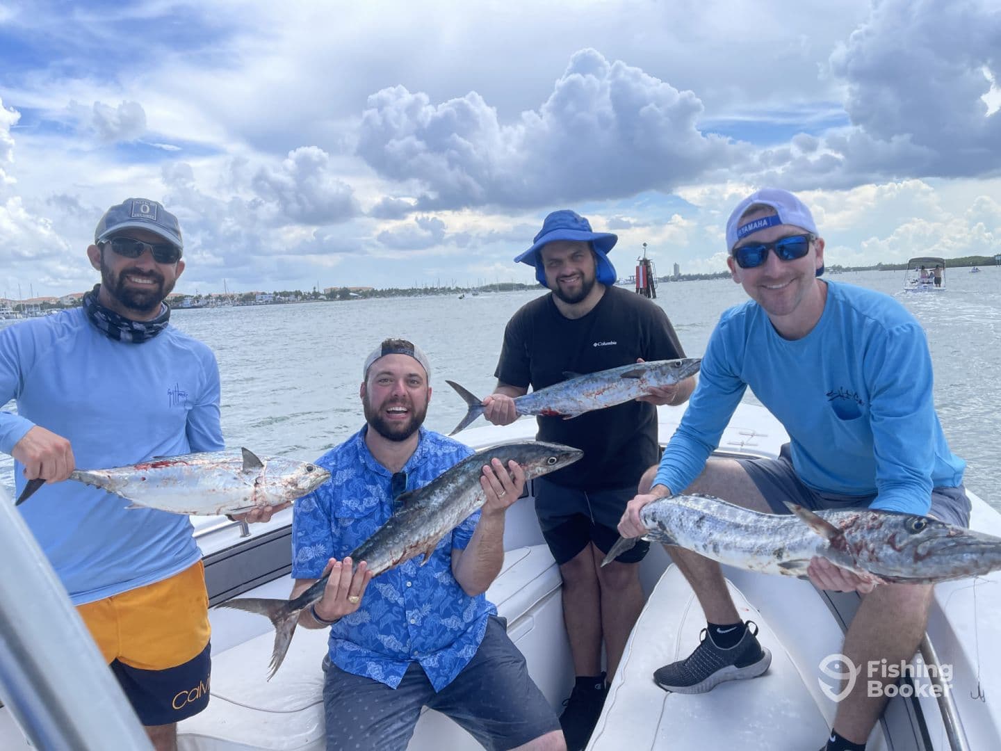Group of anglers proudly displaying their catch of King Mackerel on a boat after a successful fishing trip.