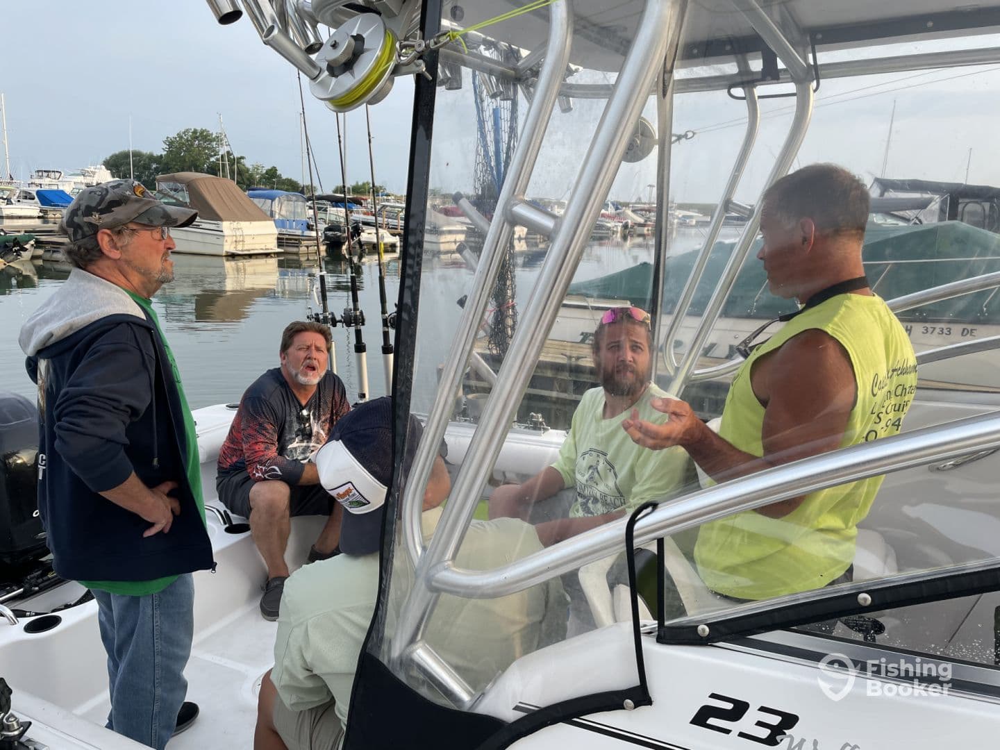 Group of anglers discussing fishing strategies inside a center console boat at the marina, surrounded by various boats.