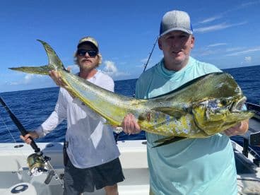 Two anglers proudly displaying a vibrant Mahi Mahi while fishing offshore, showcasing the excitement of a successful day on the water.