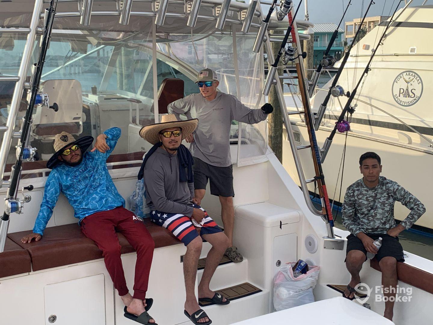 Group of anglers relaxing inside a sportfishing boat, showcasing a comfortable seating area and fishing gear.