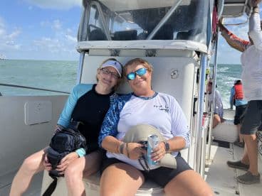 Two women enjoying a relaxing moment on the boat's seating area, surrounded by a scenic ocean view.