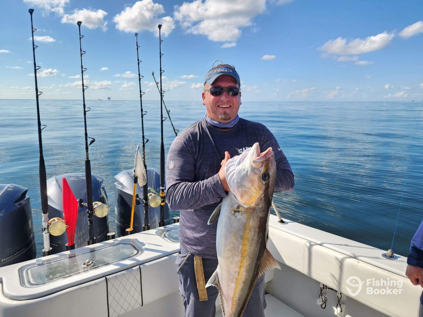 Angler proudly displaying a large fish aboard a boat in calm waters, showcasing a successful offshore fishing trip.