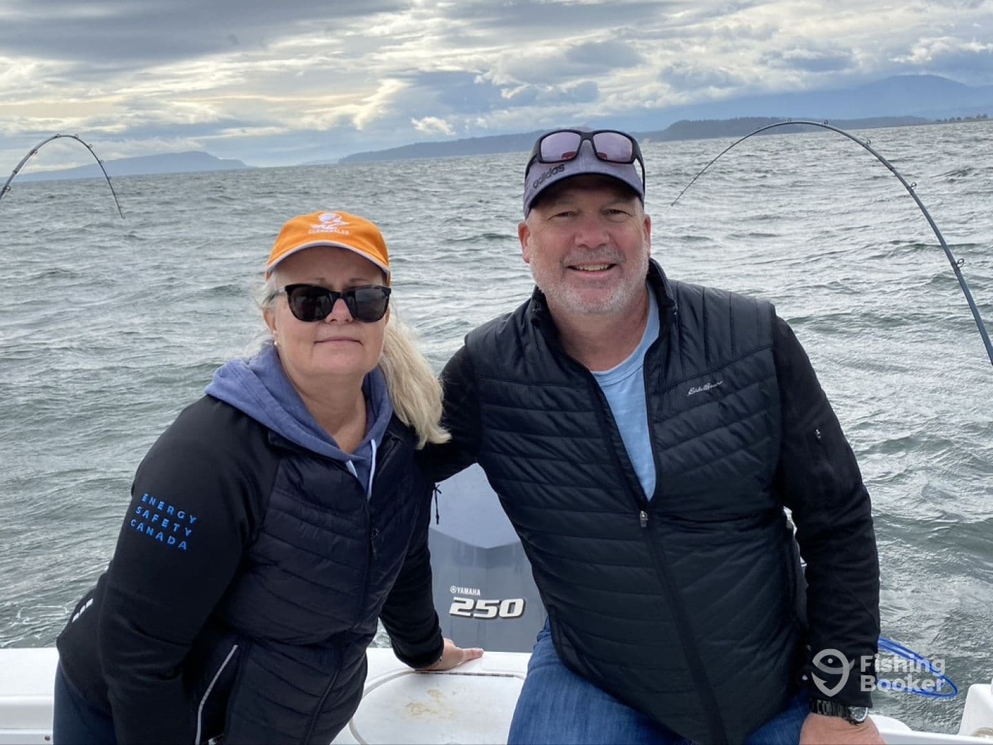 Two anglers enjoying a day on the water, with fishing rods in the background and a scenic view of the coastline.