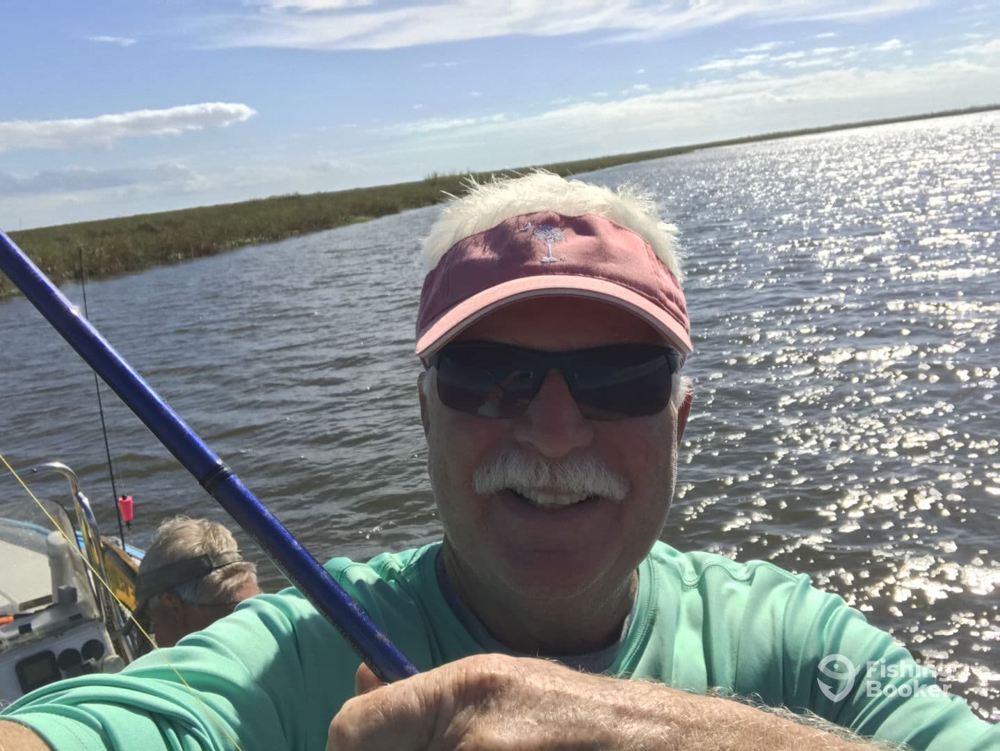 Angler taking a selfie while fishing in a scenic waterway, showcasing a relaxed day on the water.