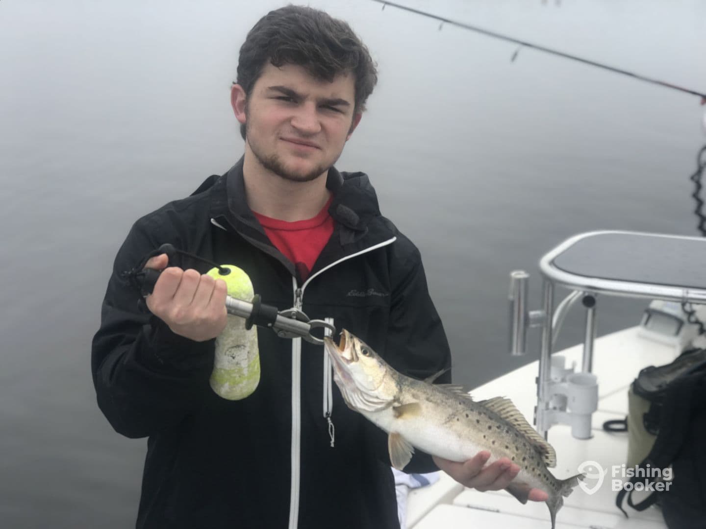A young angler proudly displaying a Speckled Trout while fishing on a foggy day.