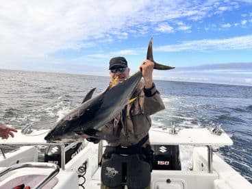 Angler proudly displaying a large Yellowfin Tuna while fishing offshore, showcasing the excitement of a successful catch.