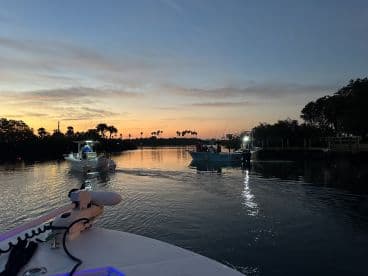 Two boats navigating through a serene waterway at sunset, showcasing a picturesque fishing environment.