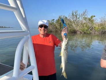 An angler proudly displaying a Snook caught while fishing in a scenic coastal area.