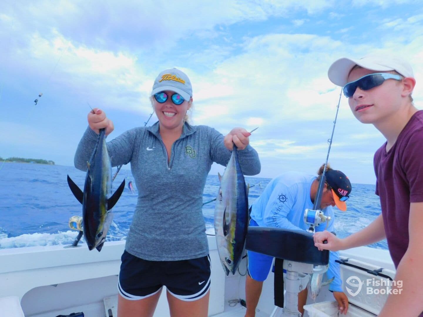 A young angler and an adult proudly displaying their catch of Yellowfin Tuna aboard a fishing boat, showcasing a successful day on the water.
