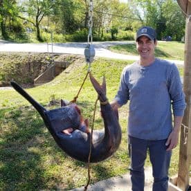 An angler proudly displaying a large catfish caught during a fishing trip, showcasing the excitement of a successful catch.